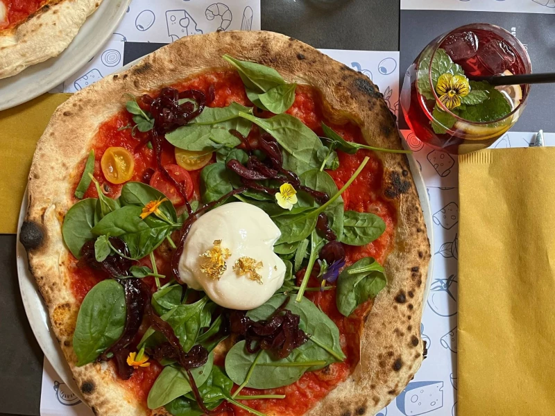 Pizza with Burrata Baby Spinach and Gold and a violet drink
